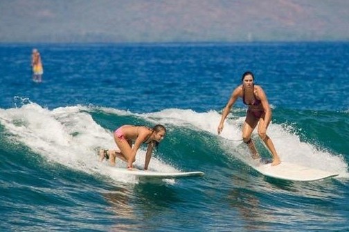 a small girl riding a wave on a surfboard in the water